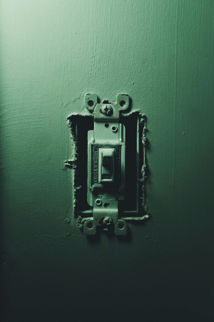 Detailed focus on an old light switch against a dark background, showcasing age and wear.
