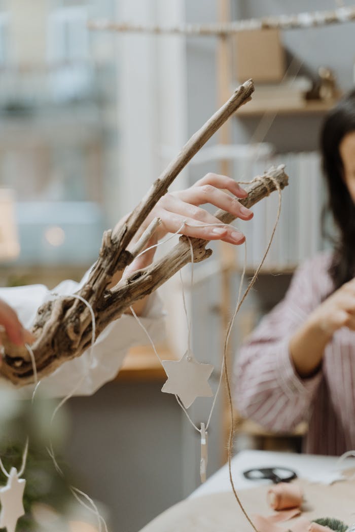 Close-up of people crafting star-shaped decorations using natural materials indoors.