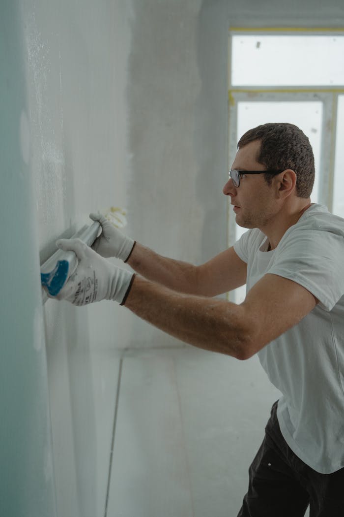 A focused worker applying drywall compound during a home renovation project indoors.