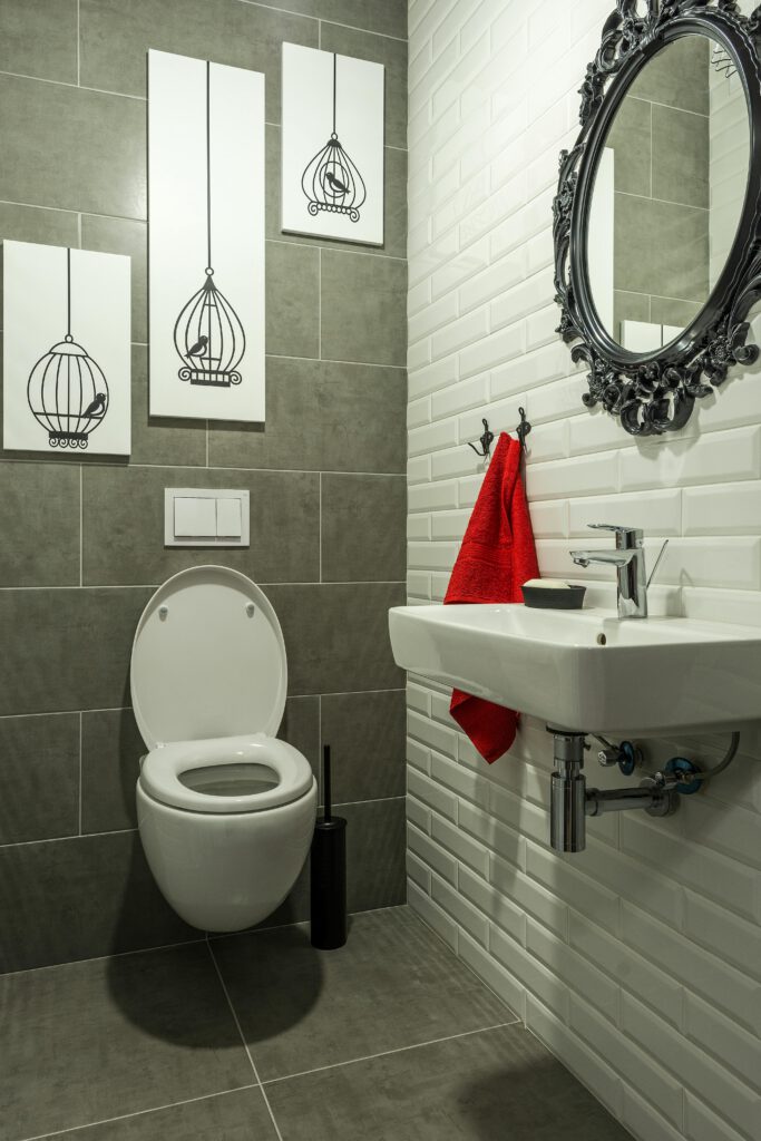 A sleek bathroom featuring gray tiles, white fixtures, and a vibrant red towel.