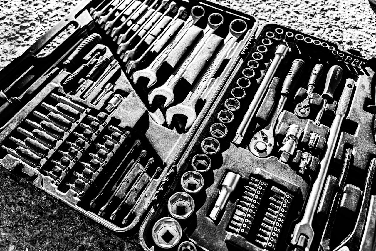 Close-up black and white photo of a complete wrench and socket tool set within a toolbox.